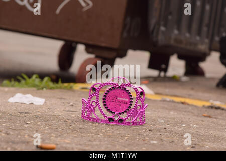 Verworfen Geburtstag Prinzessin Krone auf einem Bürgersteig mit Müllcontainer und Wurf verschwommen in das Bokeh. Stockfoto