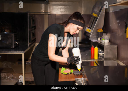 Frau Koch bereitet einen Burger in der Küche Stockfoto