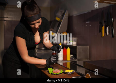 Frau Koch bereitet einen Burger in der Küche Stockfoto