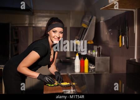 Frau Koch bereitet einen Burger in der Küche Stockfoto