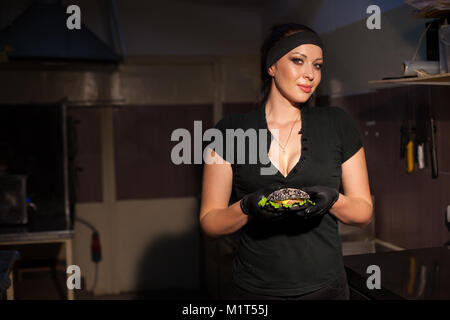 Frau Koch bereitet einen Burger in der Küche Stockfoto