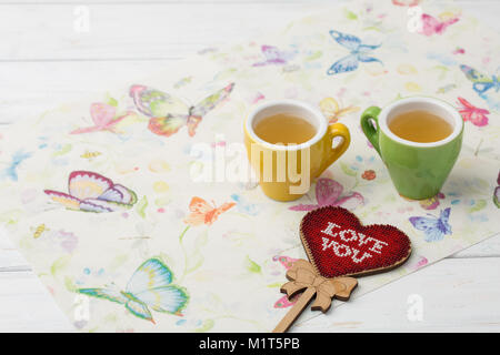 Bild mit bunten Herzen Form und ein paar Tassen Tee auf eine Serviette mit Schmetterlingen. Valentine's Day Feier Konzept. Stockfoto