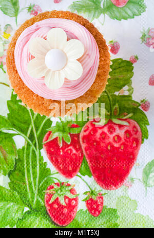 Hausgemachte Kuchen Kuchen mit Strawberry rosa Glasur Puderzucker und Reispapier genießbare daisy flower oben auf Erdbeere themed Serviette serviette Stockfoto