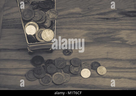 Geschäftliche und Finanzielle Konzept: Verschiedene Geld Münzen (Baht) in Gelb mini Warenkorb oder Supermarkt Trolley neben Haufen Geld Münzen. Stockfoto