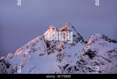 Sonnenlicht berühren die oberen der schneebedeckten Berge in Nordland, Norwegen Stockfoto