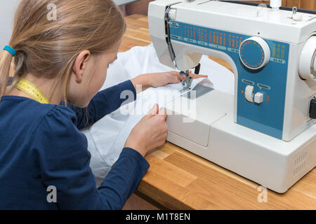 Ein 8 jähriges Mädchen ist das Nähen eines weißen Textilen Stockfoto