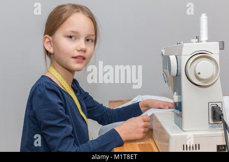 Porträt eines 8 Jahre alten Mädchen nähen eine rosa-weiß gestreiften Tuch mit einer Nähmaschine, lächelnd Stockfoto