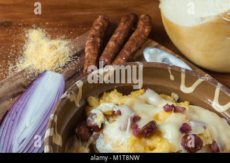 Polenta mit Käse und Wurst auf rustikalen Holztisch Stockfoto