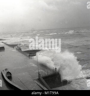 1950, historische, England, starke Winde und stürmischen Wetter große Wellen, die zum Absturz über der Bahnhofshalle oder direkt am Meer an der Küste. Stockfoto