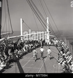 1950, historische, beobachtet von ihren Mitreisenden in Liegestühlen sittign, drei Männer an einem Wettlauf auf dem Deck eines Union-Castle Mail Steamship nehmen, wie es den Ozean unter der Leitung für das Kap in Südafrika Salis. Stockfoto