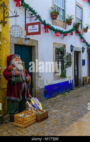 OBIDOS, PORTUGAL - Dezember 28, 2017: Blick auf eine Gasse in der Altstadt, mit den lokalen Unternehmen und Weihnachtsschmuck, in Obidos, Portugal Stockfoto