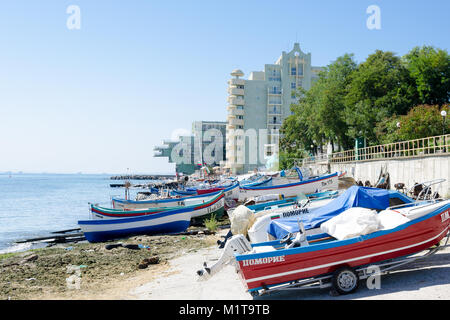 Pomorie, Bulgarien - 20. September 2014: Gruppe von kleinen Fischerbooten am Ufer mit einem Hotel auf dem Hintergrund ähnlich einem Wasserfahrzeug Stockfoto