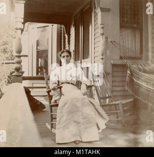 Antike ca. 1905 Foto, Frau in einem Schaukelstuhl auf der Veranda. Lage unbekannt, wahrscheinlich New England, USA. Ich habe weitere Fotos von dieser Familie in Riggsville (jetzt Robinhood), Maine in der Sagadahoc County, USA. Stockfoto