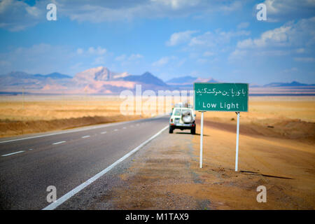 Straßenschilder in Iran, sind auf Farsi, um steinigen Hell orange Wüste, die Berge und den blauen Himmel sind teuer, das Auto kostet an der Straße Stockfoto