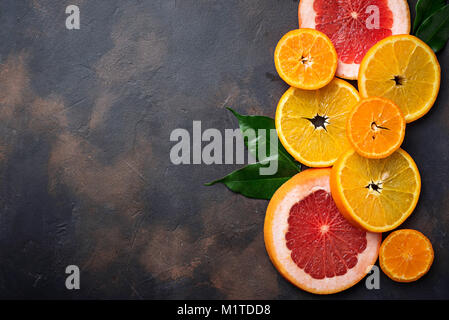 Verschiedene aufgeschnittene Zitrusfrüchte auf dunklen konkreten Hintergrund Stockfoto
