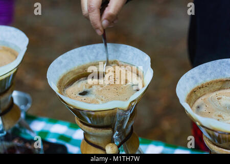 Barista rührt über Kaffee in artisan Glas Brauerei gießen, während draußen Stockfoto