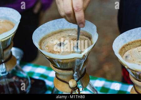 Barista rührt über Kaffee in artisan Glas Brauerei gießen, während draußen Stockfoto