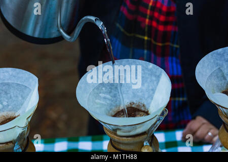 Barista gießt kochendes Wasser fron spezialisierte Wasserkocher auf Gießen über Kaffee in artisan Glas Brewer, während draußen Stockfoto