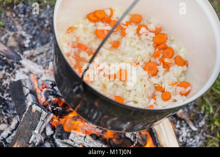 Kochen, heiße Gulaschsuppe mit Fleisch, Paprika, Kartoffeln, Zwiebeln, Karotten, traditionelle Gerichte der ungarischen Küche. Fleisch Eintopf in Römertopf zubereitet Stockfoto