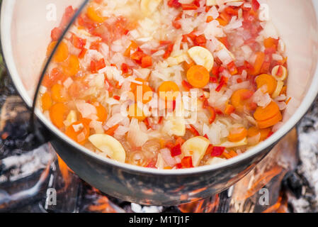 Kochen, heiße Gulaschsuppe mit Fleisch, Paprika, Kartoffeln, Zwiebeln, Karotten, traditionelle Gerichte der ungarischen Küche. Fleisch Eintopf in Römertopf zubereitet Stockfoto