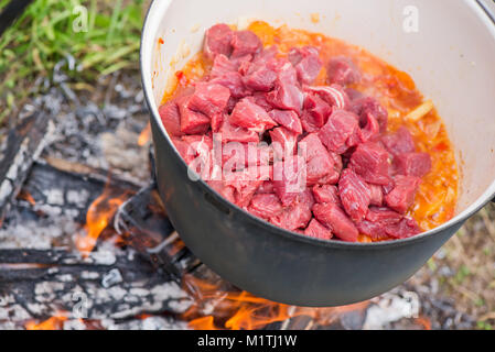 Kochen, heiße Gulaschsuppe mit Fleisch, Paprika, Kartoffeln, Zwiebeln, Karotten, traditionelle Gerichte der ungarischen Küche. Fleisch Eintopf in Römertopf zubereitet Stockfoto