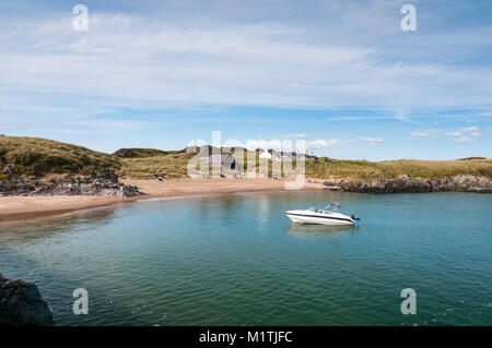 Llanddwyn Island Beach und Bucht mit Menschen am Strand und cottages Pilots im Hintergrund auf einem sonnigen späten Tag Sommer, Anglesey, Wales Stockfoto