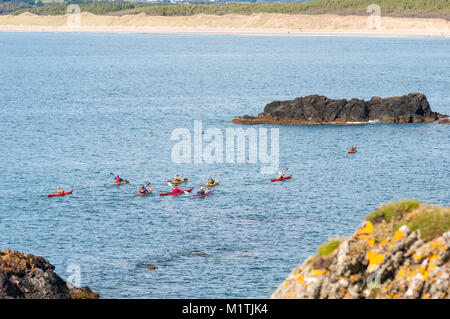 Eine Gruppe von Personen Kajak an der Küste von llanddwyn Insel in der Irischen See auf der einen späten Tag Sommer, Anglesey, Wales Stockfoto