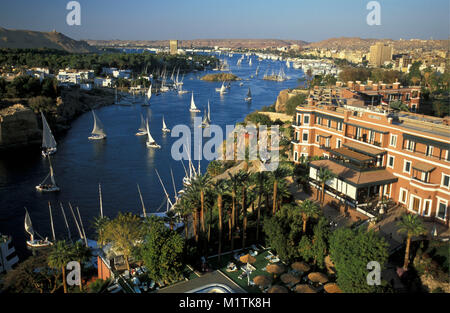Ägypten. Assuan. Nil. Feluccas (traditionelle Segelschiffe). Vor: Das Old Cataract Hotel, berühmten und historischen Hotel. Stockfoto