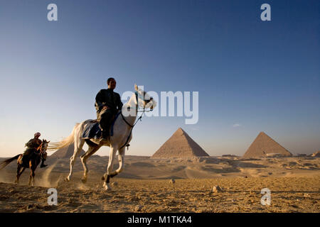 Ägypten, Kairo. Pyramiden von Gizeh oder Gizeh. Männer reiten in der Wüste in der Nähe von Pyramiden. Unesco-Weltkulturerbe. Stockfoto
