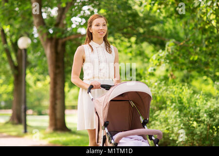 Glückliche Mutter mit Kind im Kinderwagen im Summer Park Stockfoto