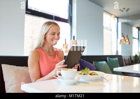 Glückliche junge Frau mit Tablet-PC im Restaurant Stockfoto