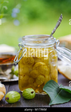 In der Nähe der stachelbeeren Stau in einem Glas auf einem Holztisch Stockfoto