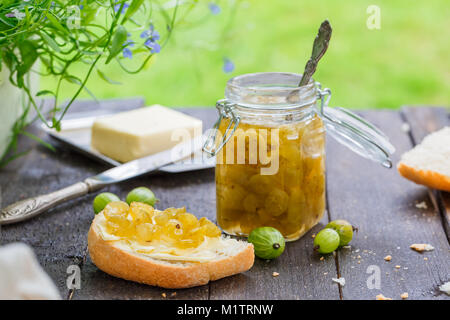 Grüne stachelbeere Stau in einem Glas auf einem Holztisch Stockfoto