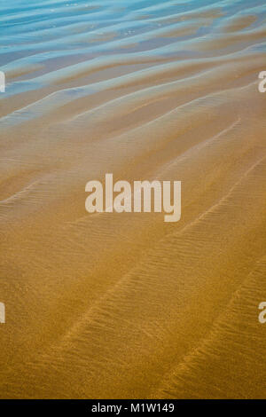 Closeup Details von einem Sandstrand mit reflektierendem blauen Himmel Stockfoto