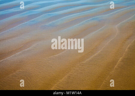 Closeup Details von einem Sandstrand mit reflektierendem blauen Himmel Stockfoto