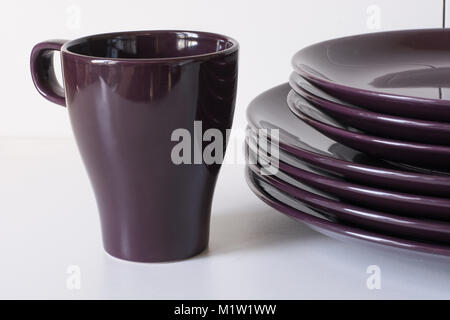 Lila Tassen und Teller auf den weißen Hintergrund. Close Up. Stockfoto