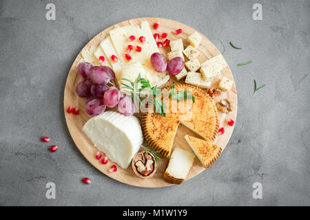 Käseplatte mit verschiedenen Käsesorten, Trauben, Nüsse über grauen Stein Hintergrund, kopieren. Italienischen Käse und Obstteller. Stockfoto