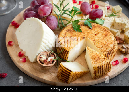 Käseplatte mit verschiedenen Käsesorten, Trauben, Nüsse über grauen Stein Hintergrund, kopieren. Italienischen Käse und Obstteller. Stockfoto