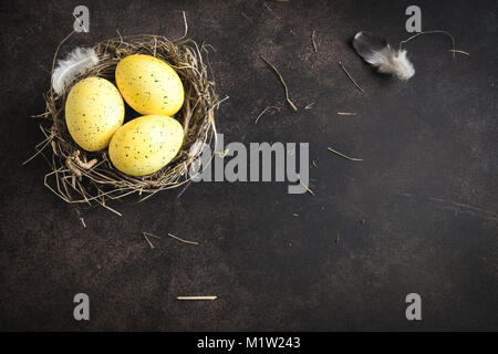 Ostereier im Nest auf rustikalen Metall Hintergrund. Verzierten Ostereier mit Federn im Nest auf braunen Tisch mit kopieren. Frühling, Ostern oder Hea Stockfoto