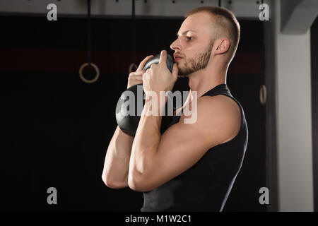 Porträt eines Athleten Mann Trainieren mit einem Wasserkocher Bell In der Turnhalle Stockfoto