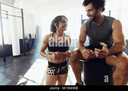 Athletisch Paar zwischen Übungen in der Turnhalle ausruhen. Glückliche junge Mann und die Frau in der Sportbekleidung im Fitnessraum entspannen nach schweren Workout. Stockfoto