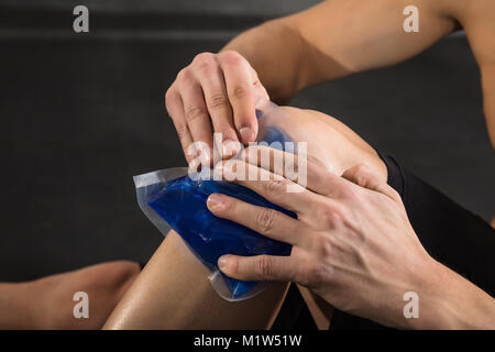 Nahaufnahme einer Person ist, die die Eisbeutel auf einem verletzten Knie in der Turnhalle Stockfoto