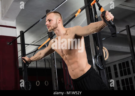 Low Angle View eines jungen Athleten Mann Trainieren mit Suspension Trainer im Fitnessraum Stockfoto