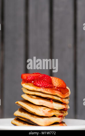 Köstliche Erdbeere Pfannkuchen auf einem dunklen Hintergrund Moody, atemberaubende Frühstück mit lebhaften Farben, weiße Platte