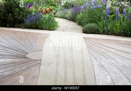 Moderne, zeitgenössische Holzterrasse mit Terrasse und gebogenem Schottergartenweg, der durch einen wilden Garten führt, Chelsea Flower Show UK Stockfoto