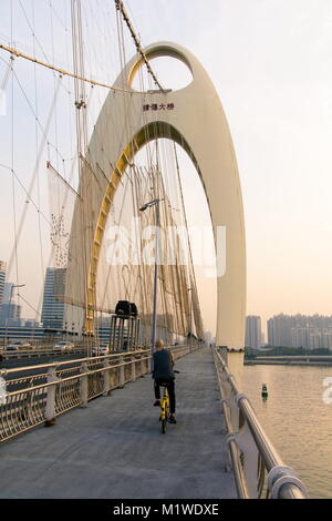 GUANGZHOU, China - 3. JANUAR 2018: Radfahrer Kreuzung Guangzhou Liede Brücke Fußgängerweg über Perl River bei Sonnenuntergang Stockfoto