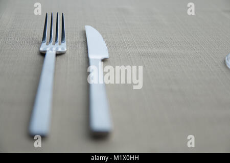 Messer und Gabel auf einem reinen grauen Hintergrund gestapelt. Stockfoto