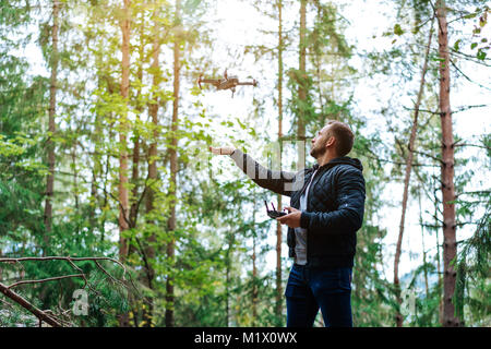 Guy startet einen quadrocopter im Wald Stockfoto