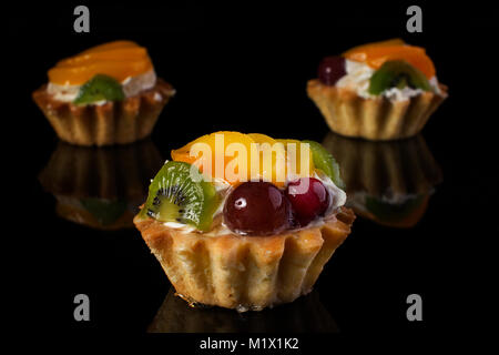 Kuchen Korb mit Kiwi pfirsich Stachelbeeren close-up auf schwarzem Hintergrund Stockfoto