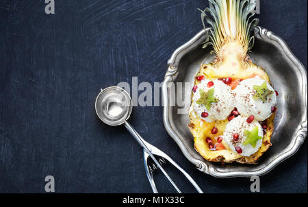 Eis in der Ananas Schüssel, dekoriert mit Kiwi und Granatapfel Stockfoto